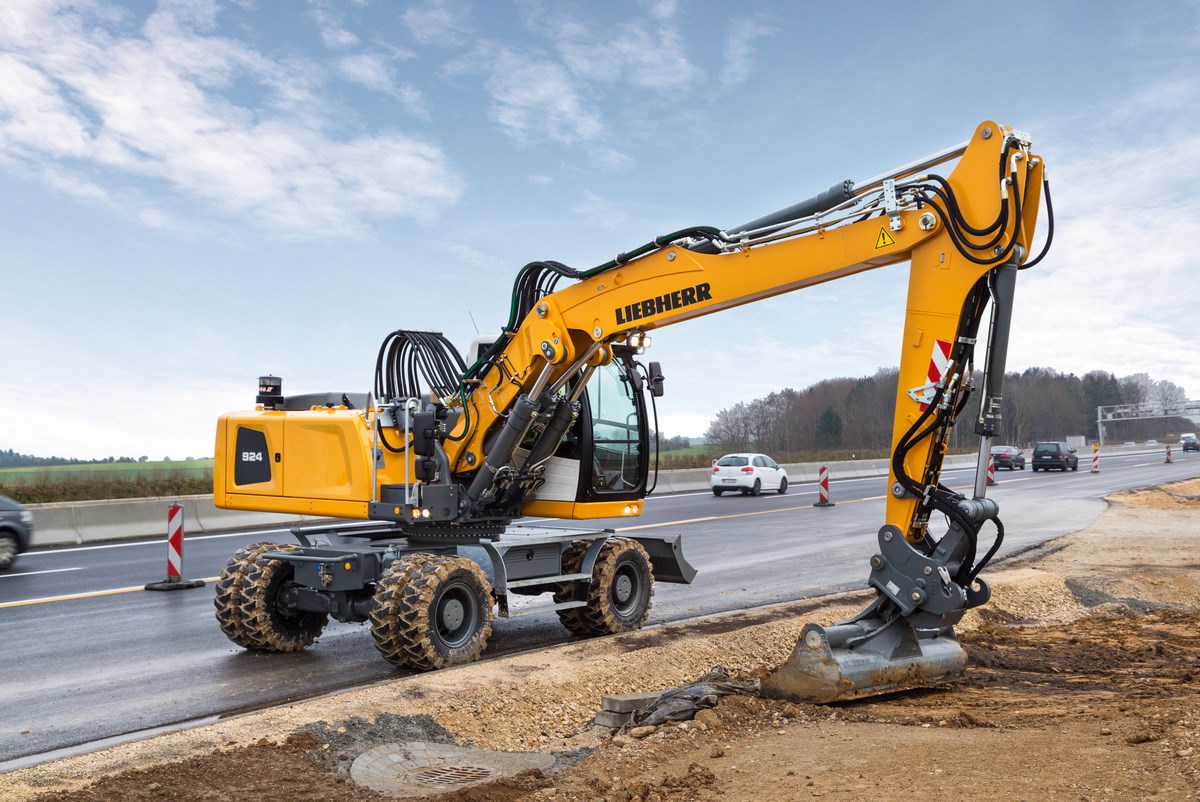 A Liebherr wheeled excavator that's parked on the side of the road while digging a small trench