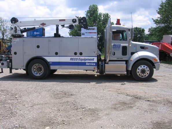 RECO Equipment service truck parked in gravel lot with other equipment in background